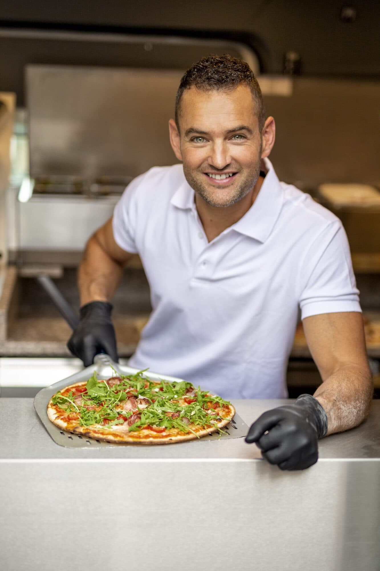 Pizzabakker schept een versgebakken pizza uit de steenoven
